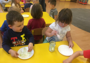 dzieci współnie przekladają cebulę i cukier do słoika