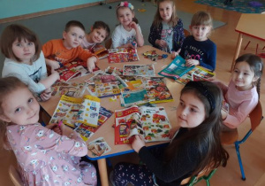 dzieci przy stoliku wycinają obrazki z gazet