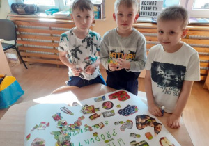 chłopcy przyklejają obrazki do ekoplakatu
