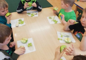 dzieci przy stoliku jedzą zielone przekąski