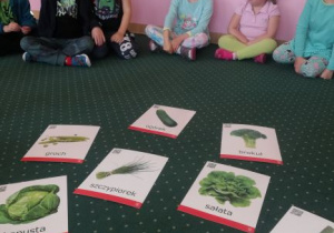 dzieci na dywanie podczas zabawy dydaktycznej nazywają i opisują zielone owoce i warzywa