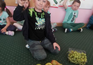 chłopiec siedzi przed tacą z owocami