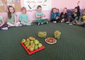 dzieci siedzą przed tacą z owocami