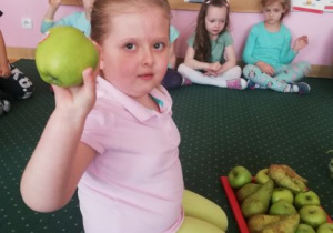 dziewczynka trzyma w ręku zielone jabłko