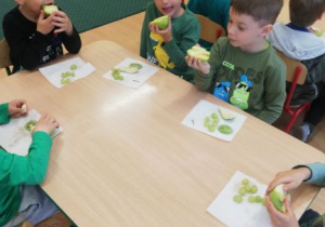 dzieci przy stoliku jedzą zielone przekąski