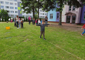 dziecko przechodzi po linie rozłożonej na trawie