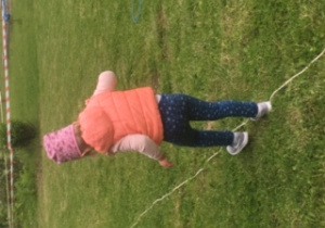 dziecko przechodzi po linie położonej na trawie