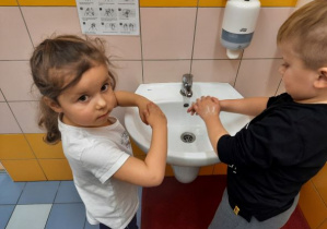 dzieci przy umywalce przypominają sobie prawidłową kolejność czynności podczas mycia rąk