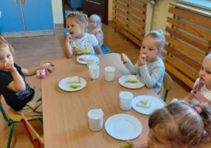 dzieci przy stolikach jedzą śniadanie