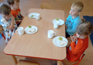 dzieci przy stolikach jedzą śniadanie