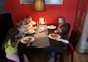 dzieci jedzą gotową pizzę