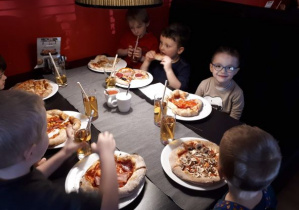 dzieci jedzą gotową pizzę