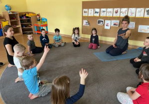 dzieci wykonują pozycje jogi zaproponowane przez instruktorkę
