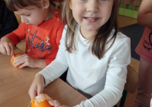 dziewczynka obiera pomarańczę