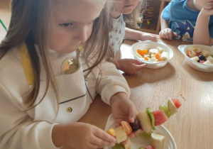 dziewczynka nabija owoce na patyczek
