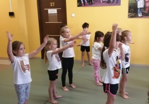 dzieci wykonują ćwiczenia na matach podczas zajęć z judo