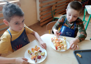 dzieci robią szaszłyki owocowe przy stolikach