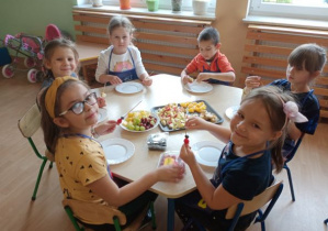 dzieci robią szaszłyki owocowe przy stolikach