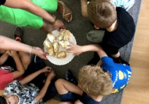 Dzieci sięgają bagietkę z talerzyka.