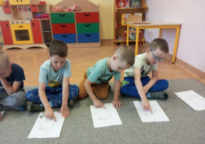 Dzieci kreślą literę o zgodnie ze strzałkami.