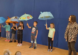 Dzieci tańczą z parasolami.