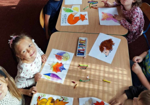 Dzieci kolorują jesienne obrazki.