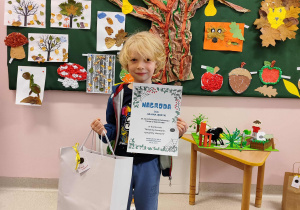 Chłopiec trzyma dyplom i nagrodę.