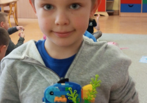 Chłopiec trzyma budowle z klocków LEGO.