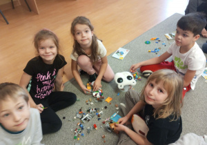 Dzieci układają budowlę z klocków LEGO.