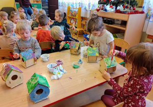 Dzieci malują kolorowe karmniki.