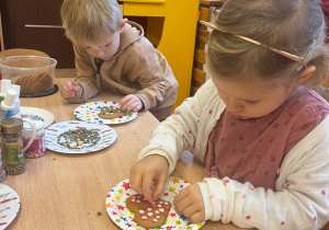 dziewczynka i chłopiec ozdabiają pierniczki