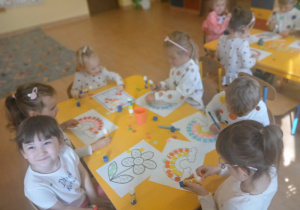 Dzieci wyklejają prace plastyczną.