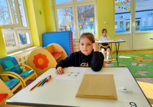 Dziewczynka siedzi przy stoliku.