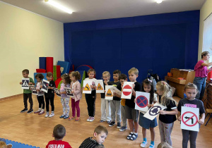 Przedszkolaki trzymają znaki drogowe.