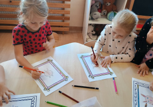 Dziewczynki rysują kredkami.