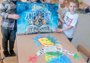 Chłopcy trzymają kolorowy plakat.