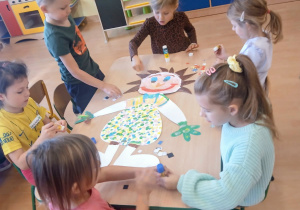 Przedszkolaki ozdabiają sylwetę kolorowego stworka.
