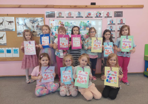 Dziewczynki z laurkami uśmiechają się.