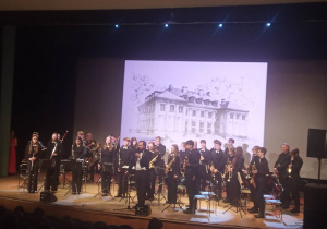 Muzycy z instrumentami stoją na scenie.