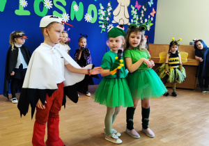 Chłopiec w stroju bociana stoi obok dziewczynek.