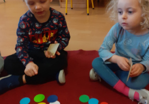 Dziewczynka i chłopiec siedzą na dywanie.