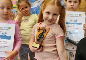 Dziewczynka trzymająca statuetkę uśmiecha się.