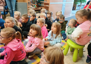 Dzieci siedzą na kolorowym dywanie.