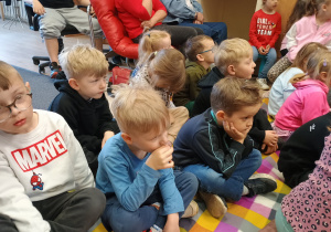 Małe dzieci siedzą na kocu.