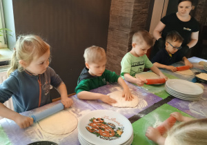 Dzieci wałkują ciasto na pizzę.