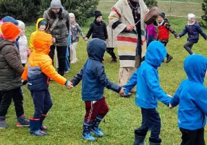 Przedszkoalki tańczą wokół mężczyzny w stroju Indianina.