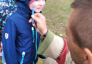 Mężczyzna maluje twarz dziewczynce.