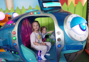 Dziewczynki siedzą w zabawkowym helikopterze.