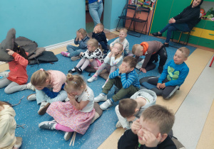Przedszkolaki z zamkniętymi oczami siedzą na podłodze.