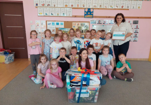 Uśmiechnięte przedszkolaki wraz z nauczycielami i prezentem.